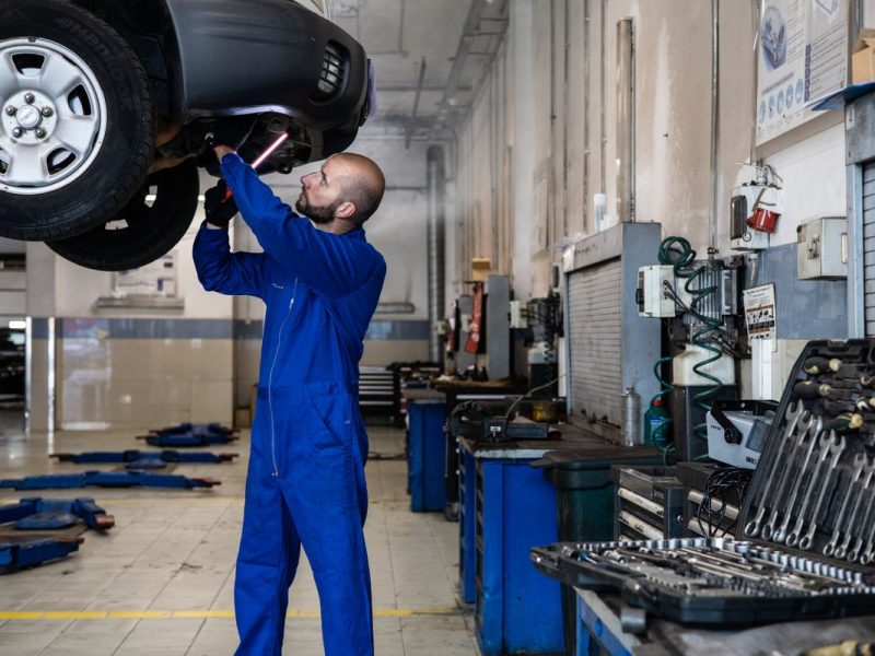 Mechaniker prüft Fahrwerk und Unterboden auf der Hebebühne