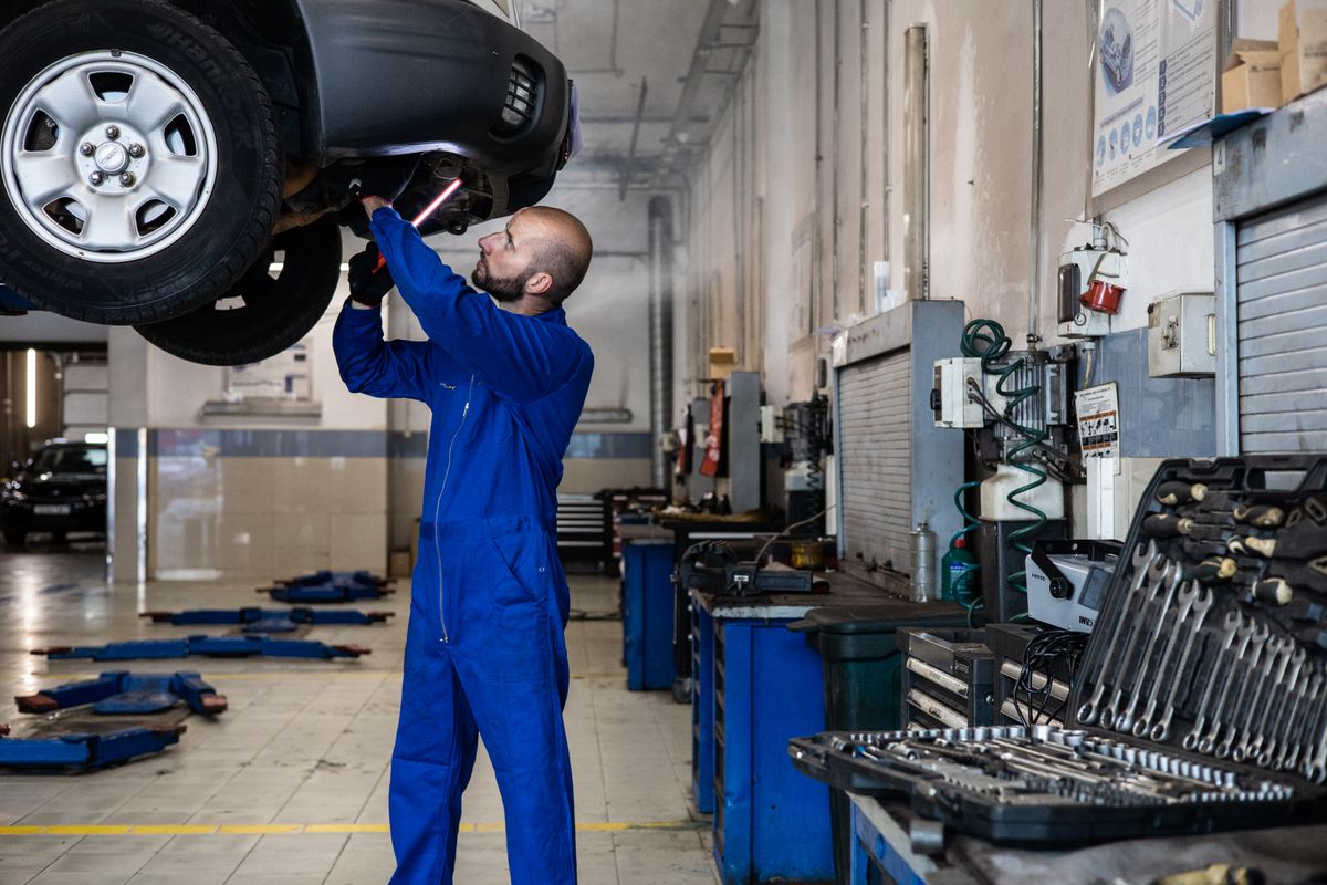 Mechaniker prüft Fahrwerk und Unterboden auf der Hebebühne